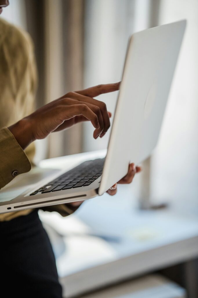 A woman uses a laptop indoors, captured in a vertical close-up shot emphasizing technology and workspace.